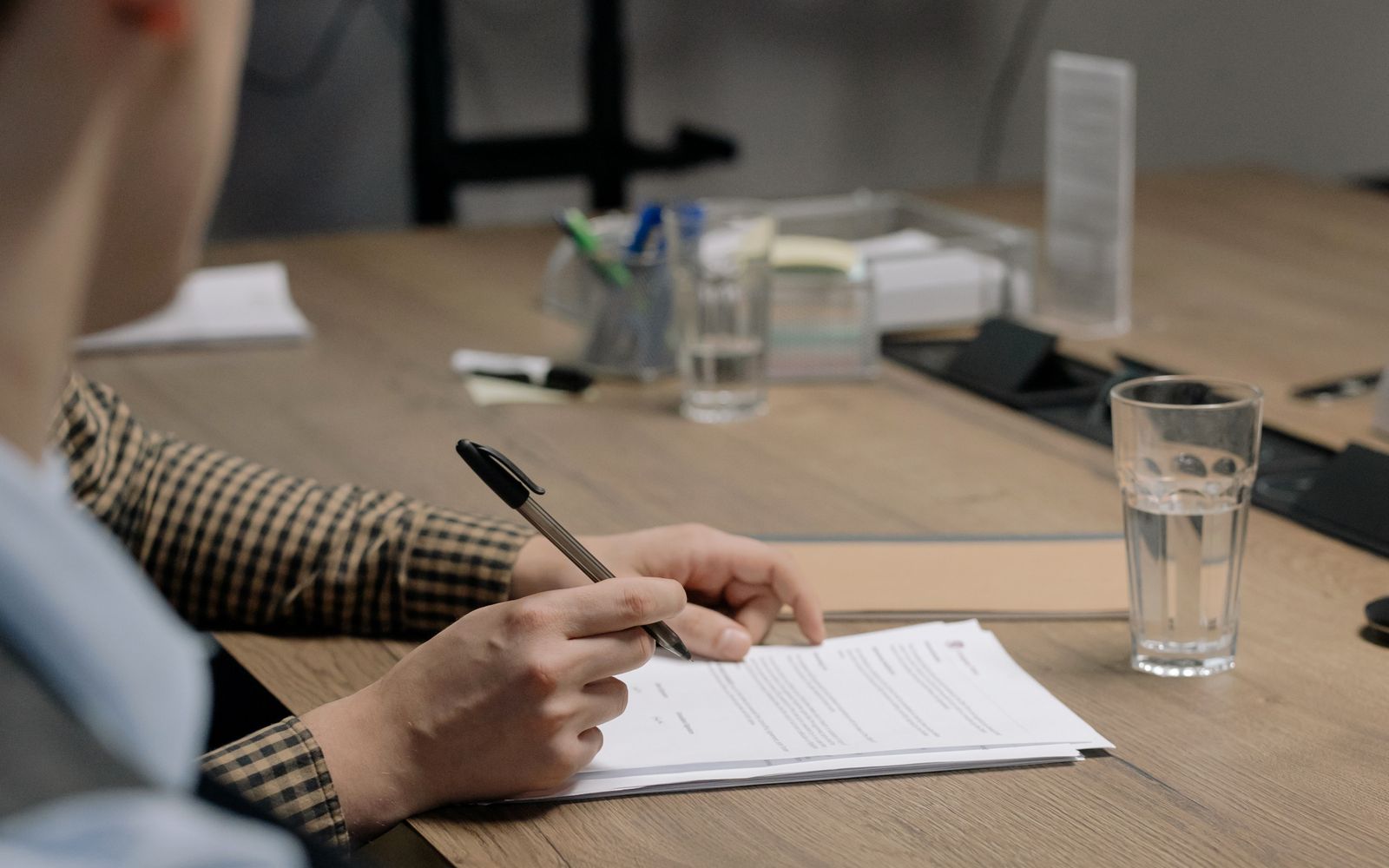 Person signing a document at a desk in an office