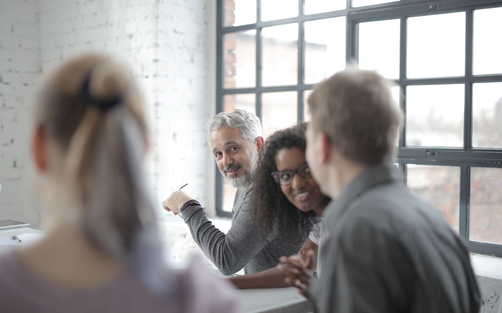 Colleagues in conversation around a table in a bright office